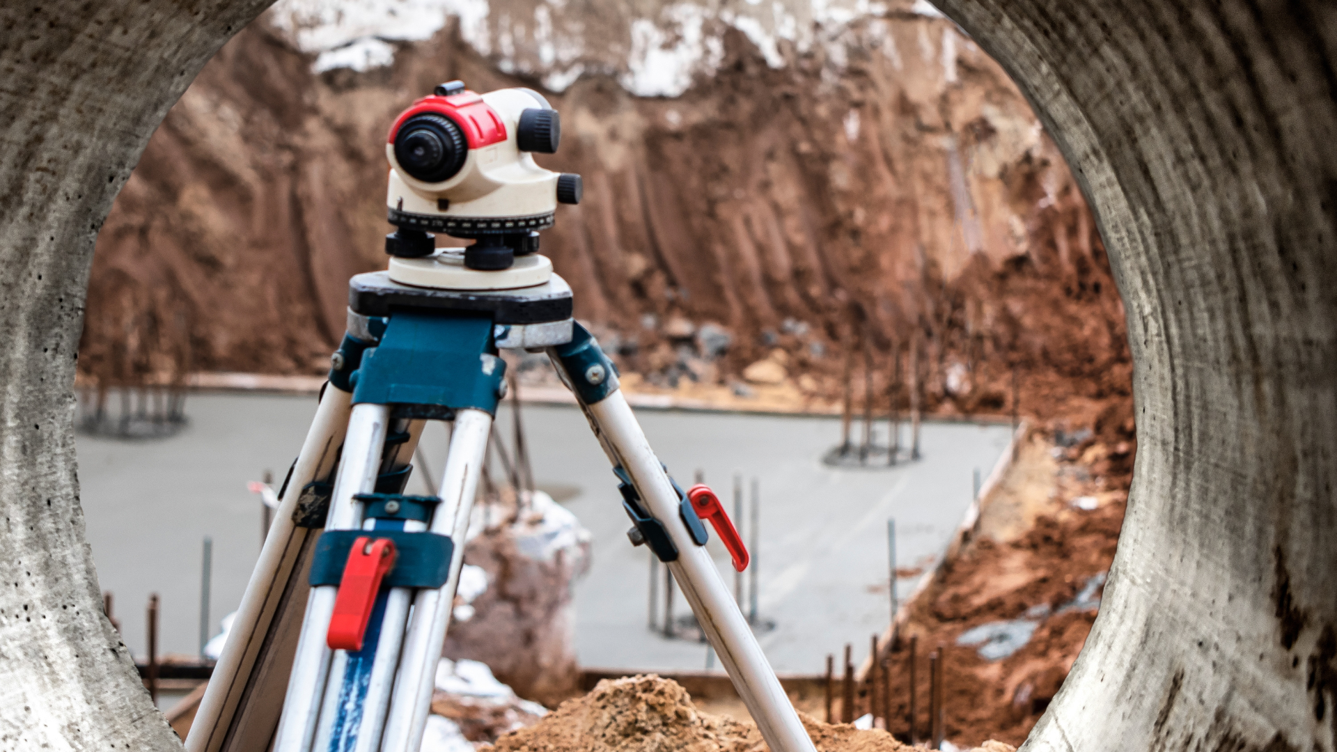 Surveyor's level on tripod viewed through a concrete septic ring